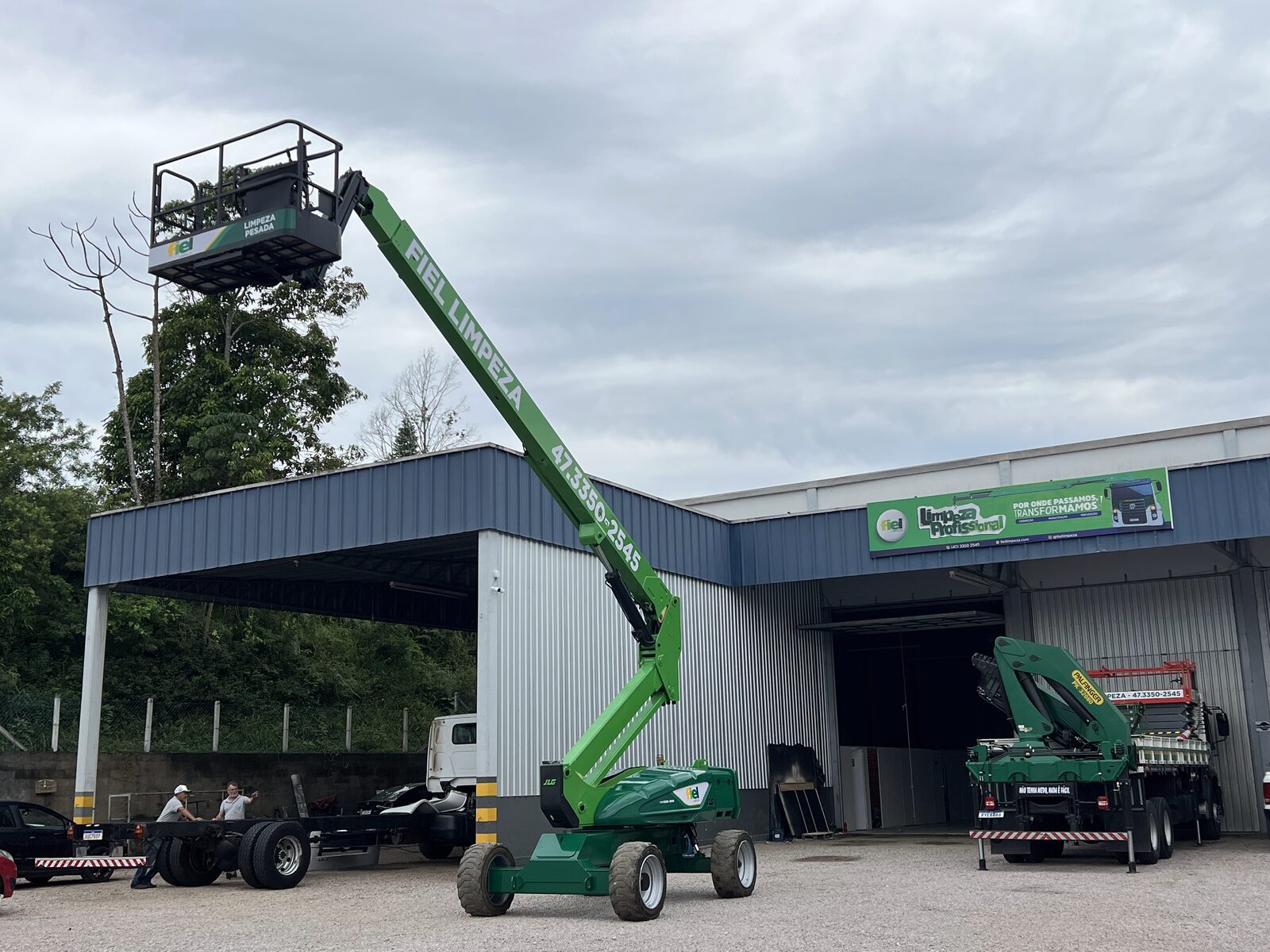 Plataforma elevatória articulada verde em frente à sede do Grupo Fiel